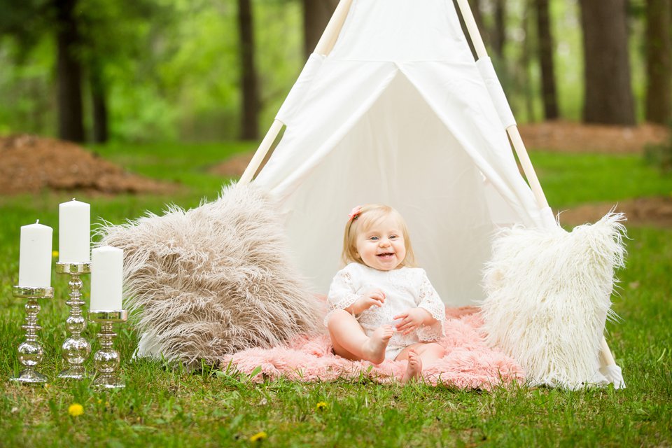 Photographs of a toddler under a teepee with fuzzy pillows