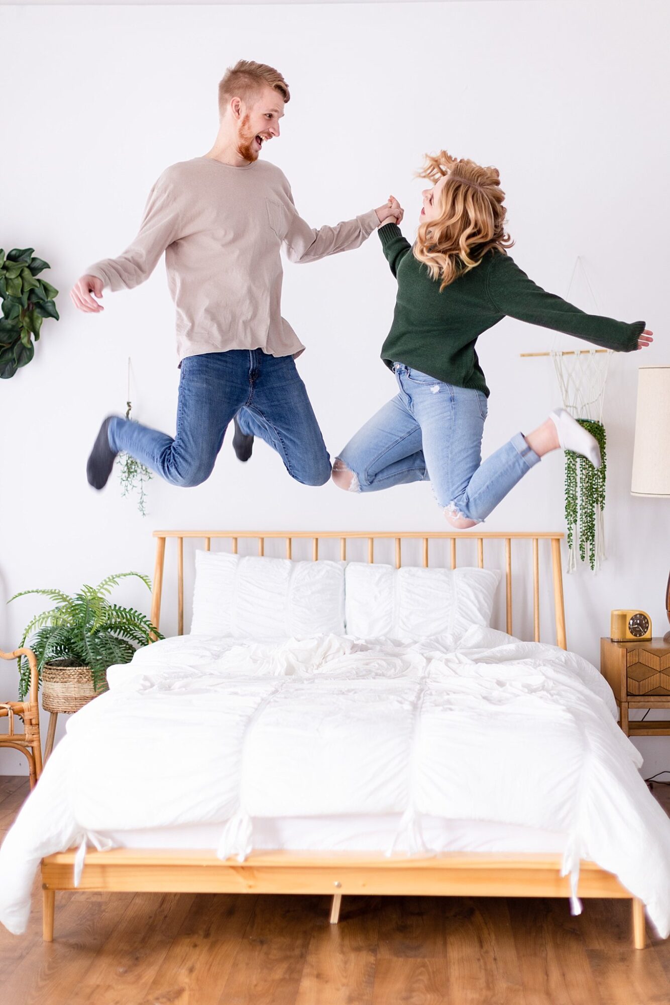 Cozy indoor engagement session jumping on a bed