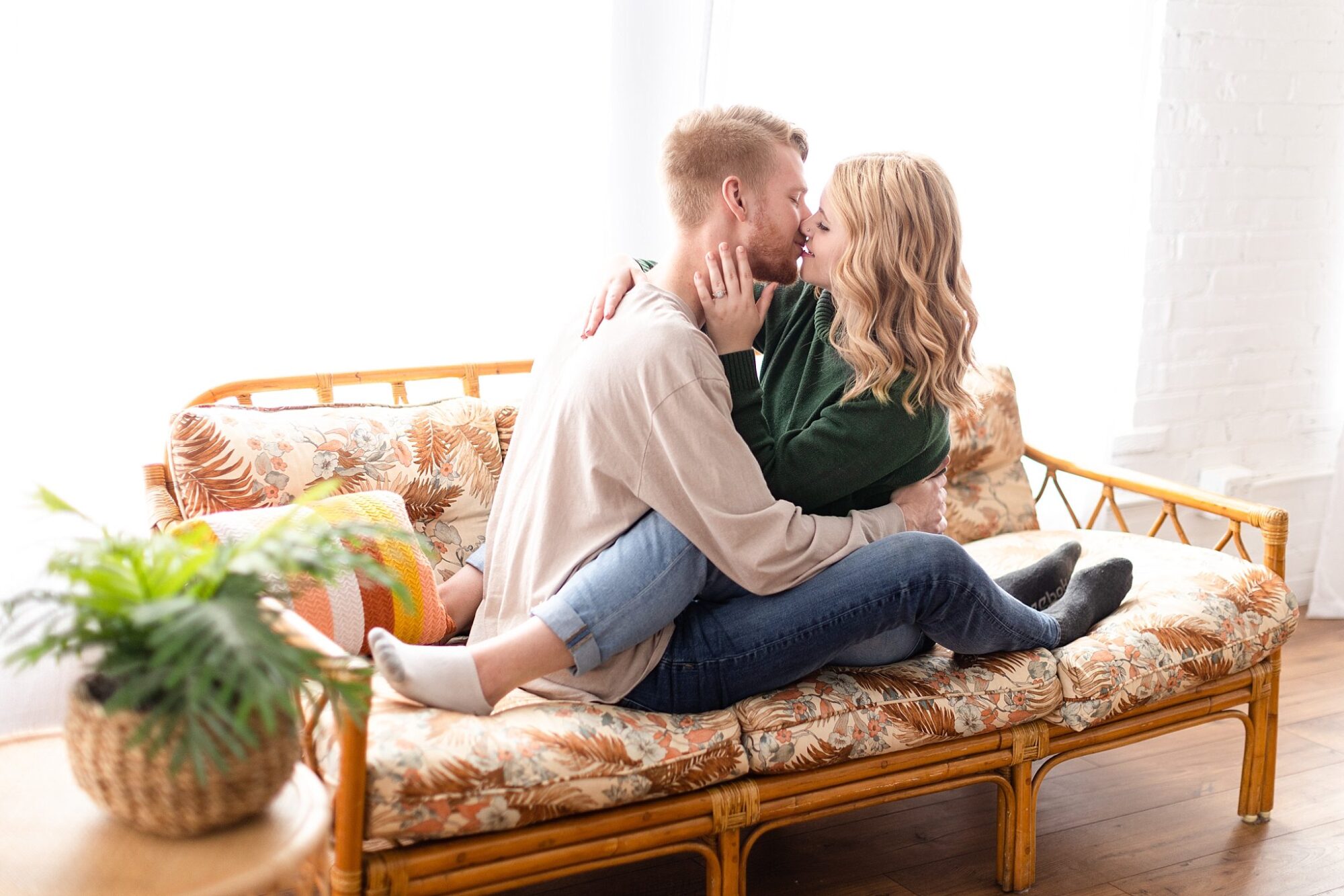 Cozy indoor engagement session cuddling on a couch