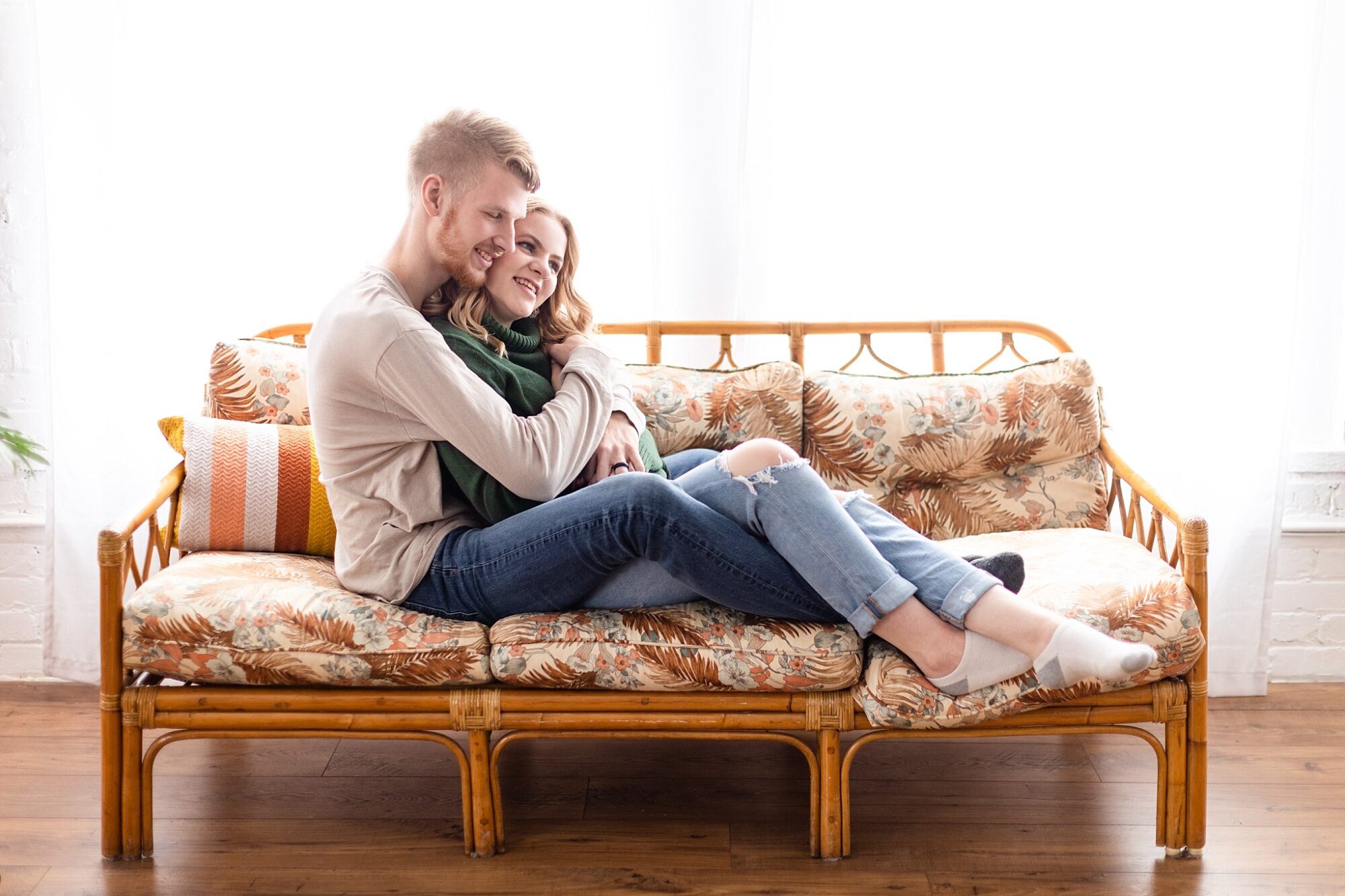 Cozy indoor engagement session cuddling on a couch